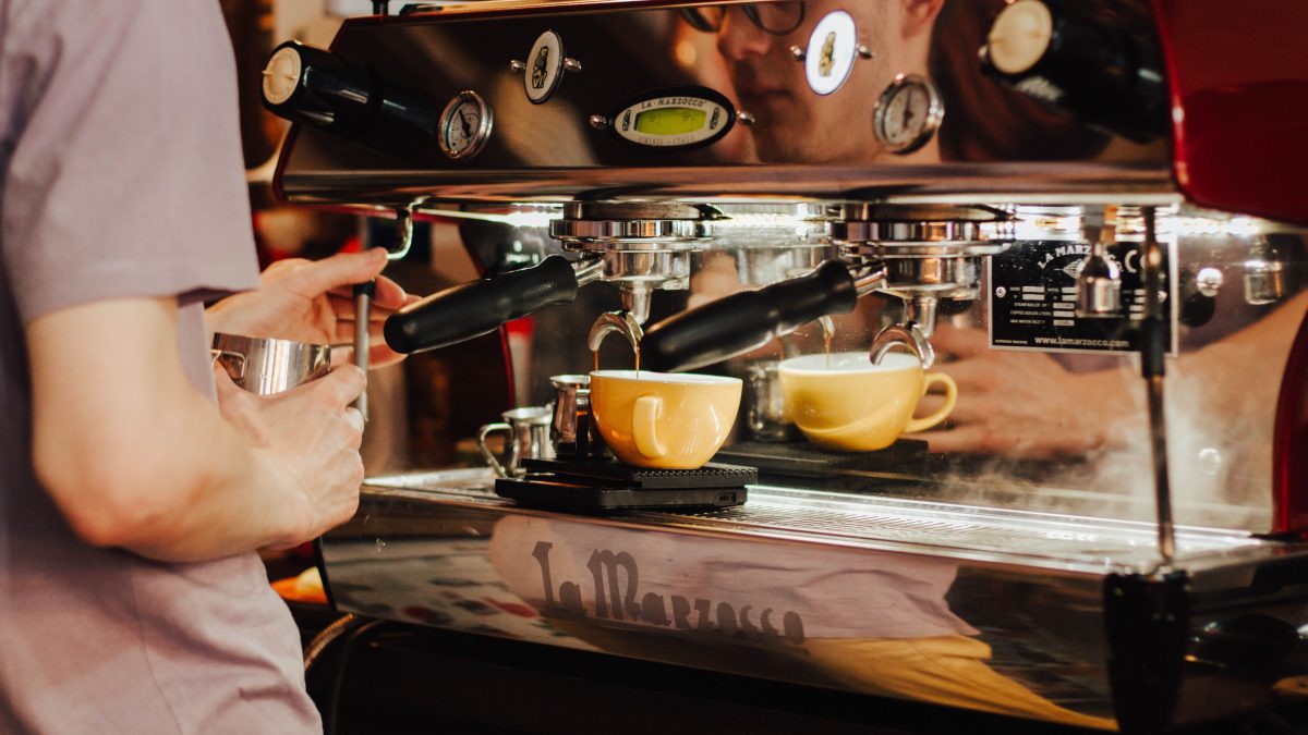 Barista using an espresso machine behind a coffee shop counter