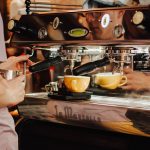 Barista using an espresso machine behind a coffee shop counter