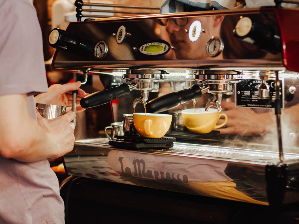 Barista using an espresso machine behind a coffee shop counter
