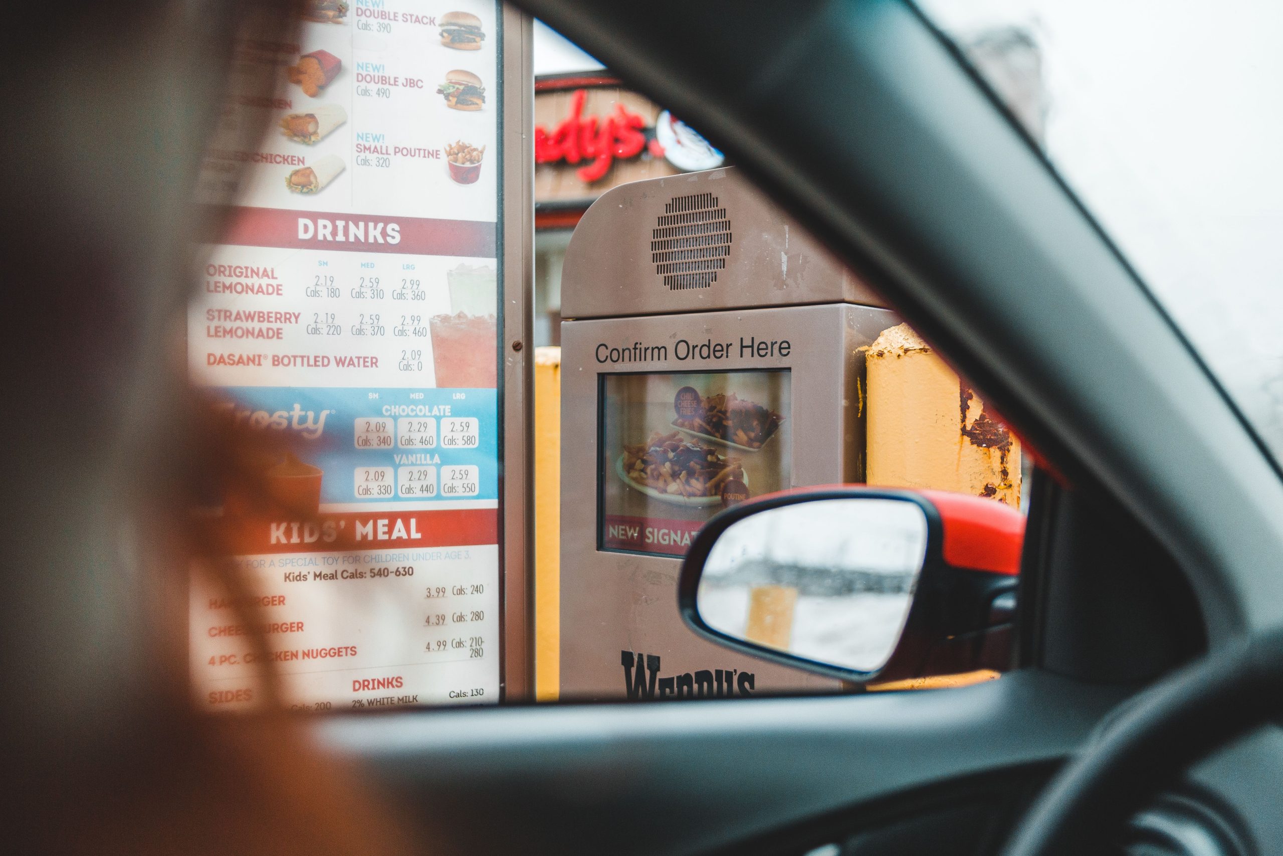 Customer ordering fast food from their car at a drive-thru menu