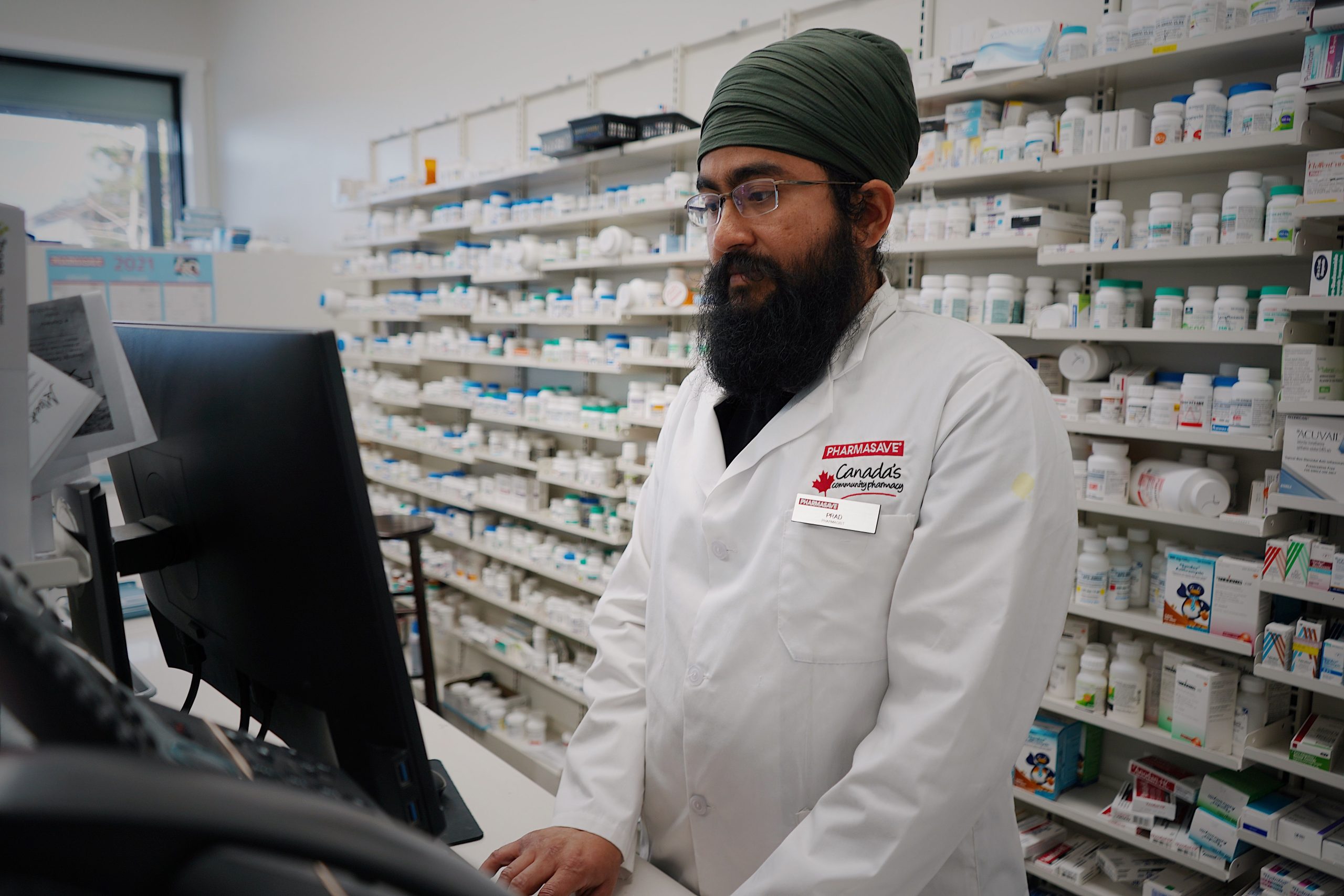 Pharmacist working at a computer counter in a pharmacy