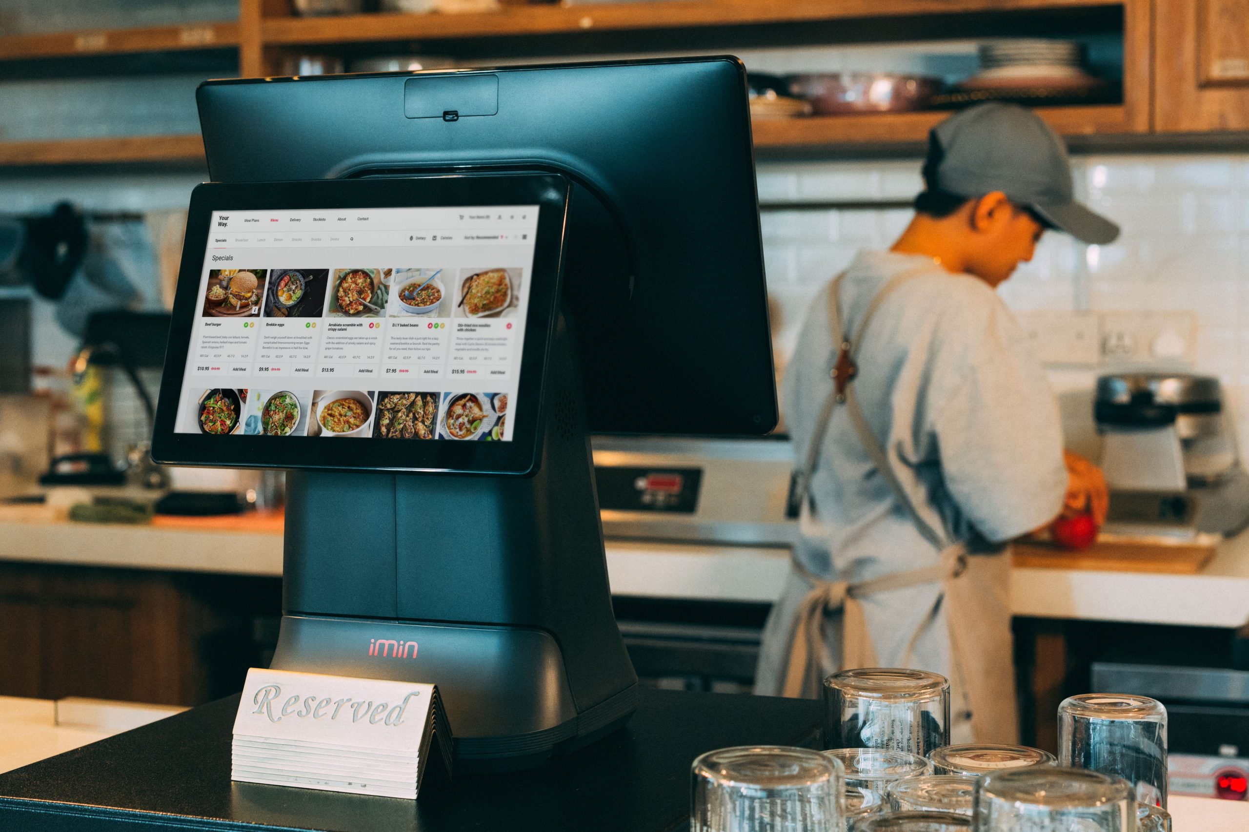 Kitchen display system showing digital orders as a chef works in a restaurant kitchen