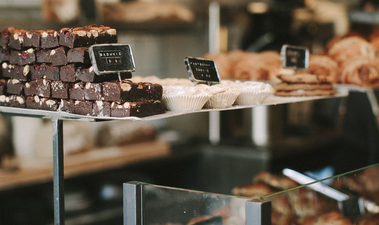 How Bakery POS Software Reduces Daily Waste and Manages Custom Cake Orders 8 Pastries and cakes arranged in a glass bakery display counter