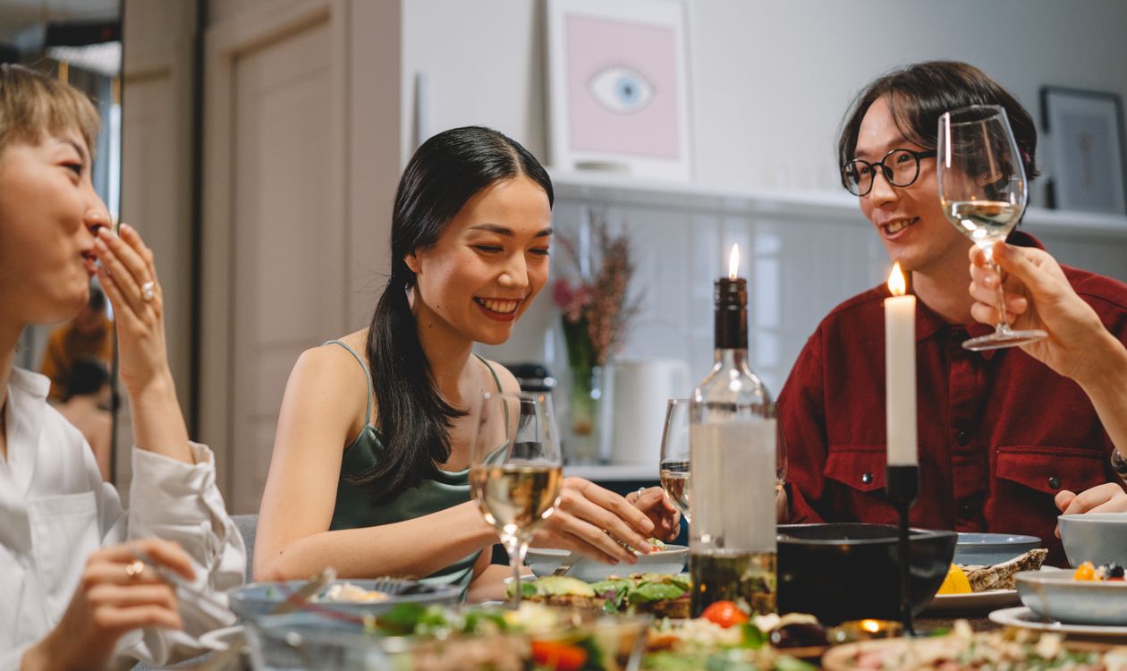 Friends sharing a meal at a candlelit restaurant table in the evening